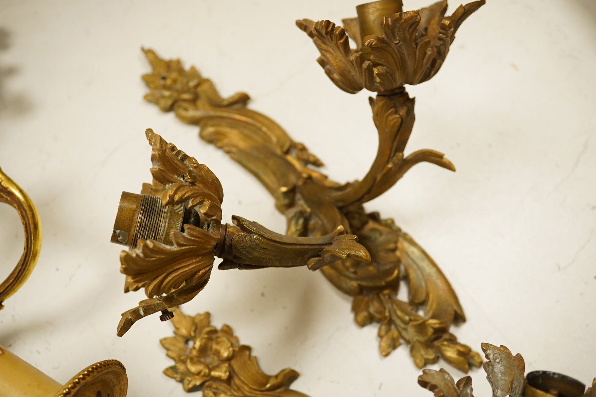 An ormolu ceiling light, a pair of three branch sconces and two pairs of two light sconces, largest 38cm high. Condition - variable